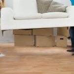 Happy Young Couple Carrying Couch In New Home